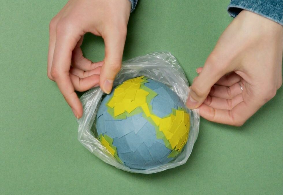 Lehrerinnenhände halten Weltkugel aus Papier in Plastik