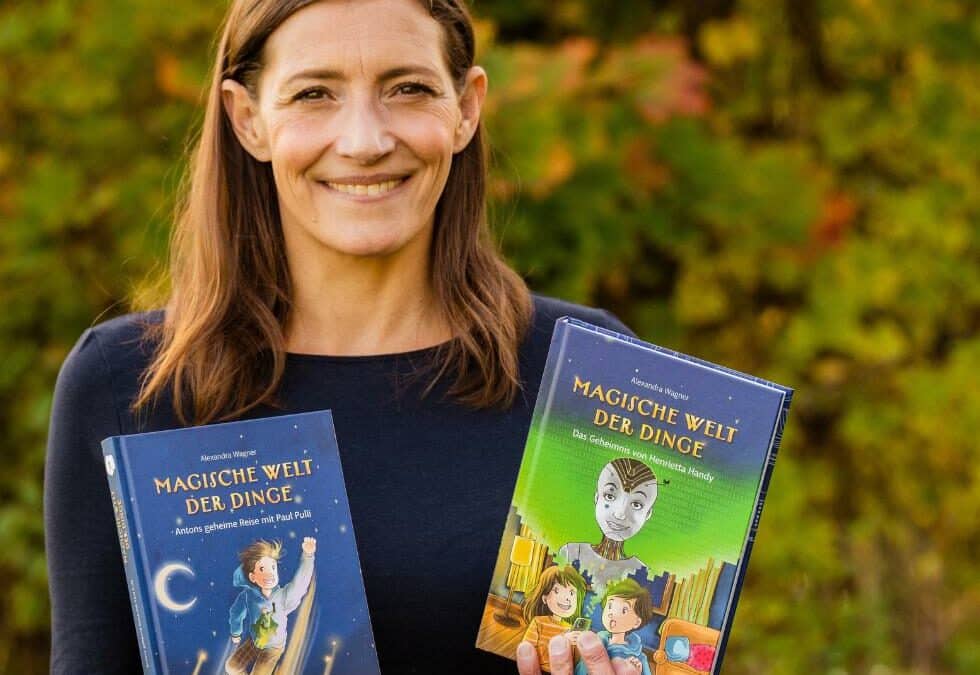 Autorin Alex Wagner hält zwei Bänder der Kinderbuchreihe über Nachhaltigkeit "Magische Welt der Dinge" in die Kamera