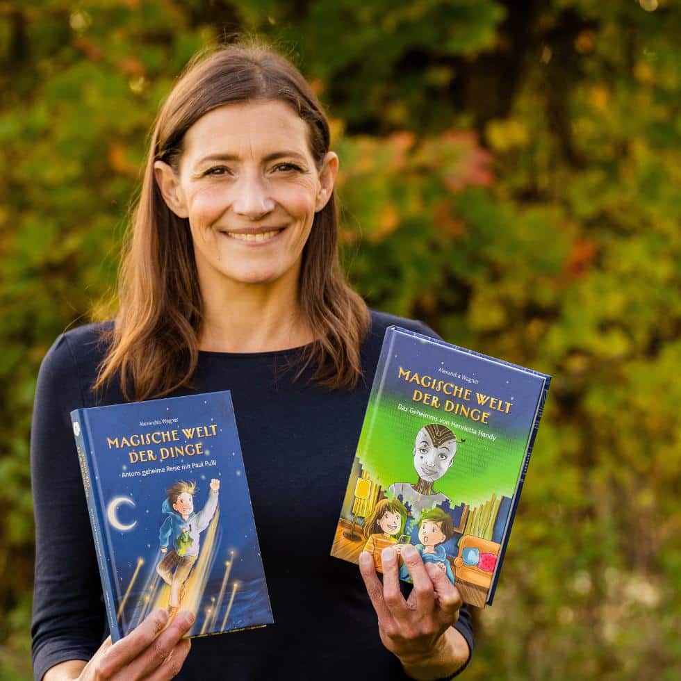 Autorin Alex Wagner hält zwei Bänder der Kinderbuchreihe über Nachhaltigkeit "Magische Welt der Dinge" in die Kamera