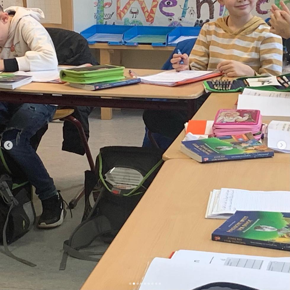 Kinder im Klassenzimmer mit Kinderbuch "Magische Welt der Dinge, das Geheimnis von Henrietta" auf Tischen