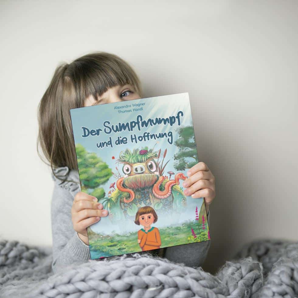 Mädchen hält Kinderbuch über Angst »Der Sumpfmumpf und die Hoffnung« vors Gesicht