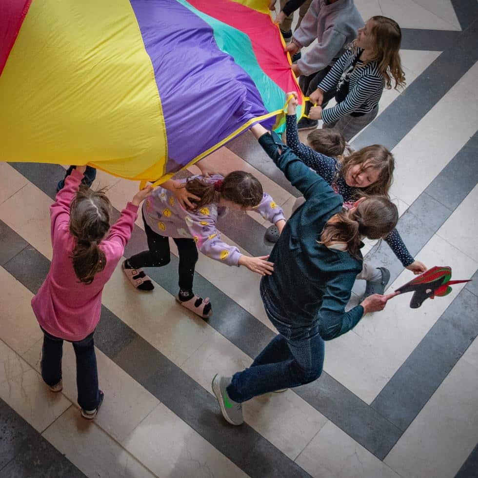 Alexandra Wagner läuft mit Kindern unter einem Schwungtuch durch