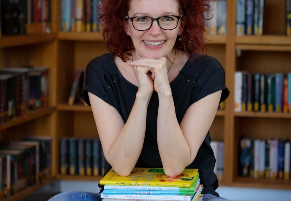 Lese- und Literaturpädagogin Sinnwell-Backes mit eigenen Büchern auf Schoß