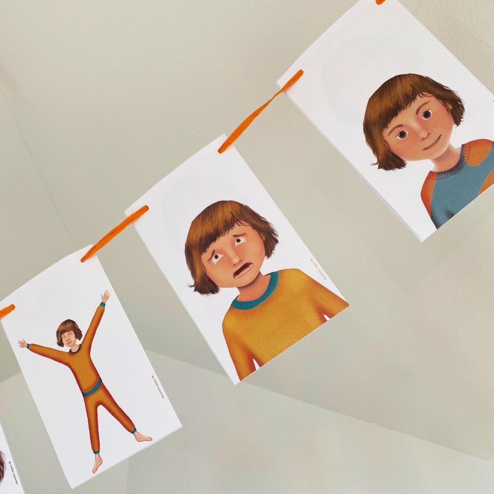 gefuehlskarten-angst-stolz-ruhe-ohne-beschriftung-aufgehaengt Gefühlskarten mit Gesichtern, die Stolz, Angst und Ausgeglichenheit zeigen und an einer Schnur aufgehängt sind.