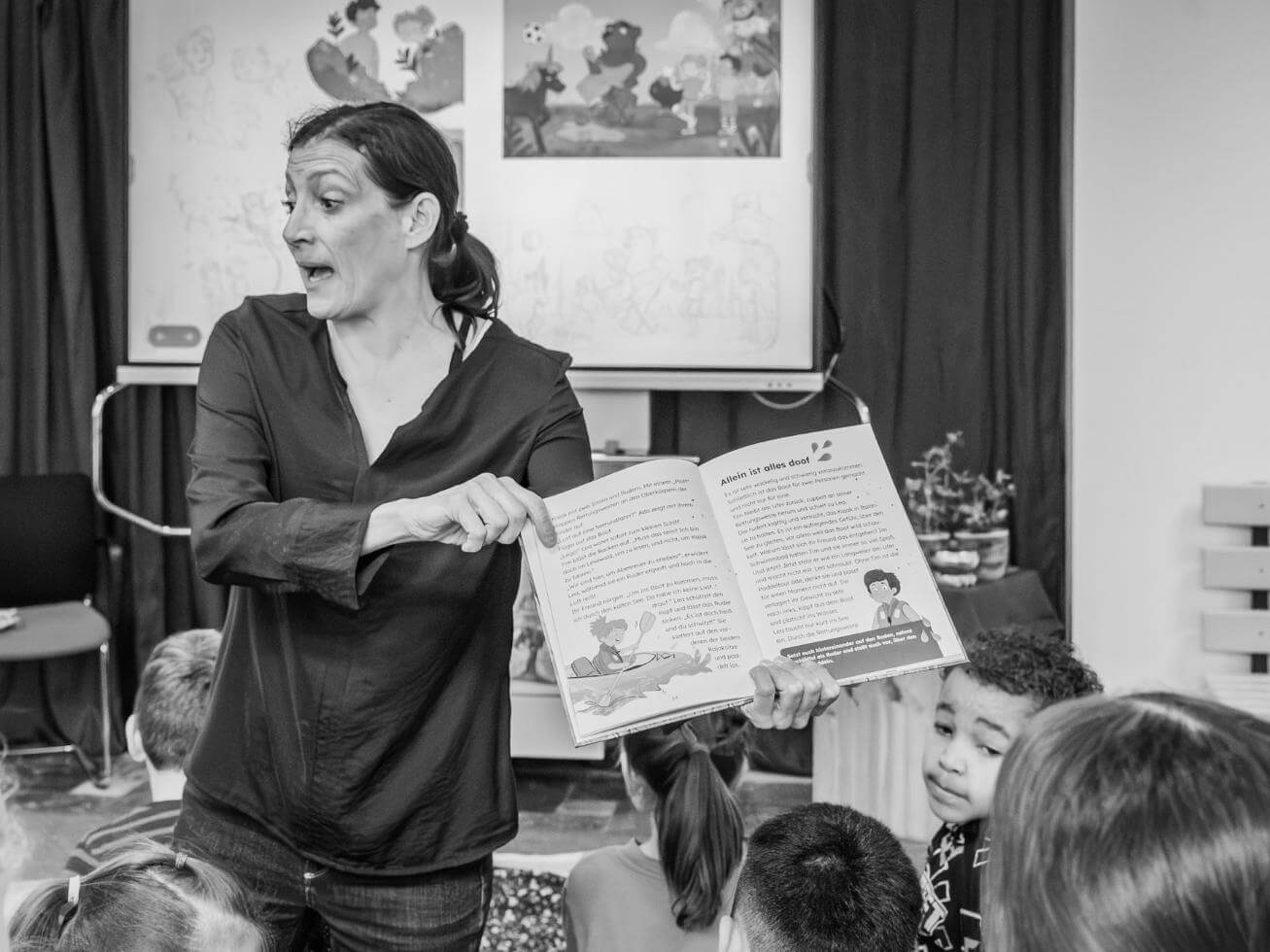 Alex Wagner zeigt aufgeschlagenes Buch und erzählt Publikum dazu etwas