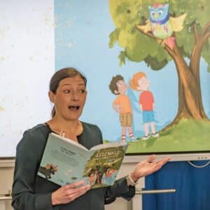 Autorin Alexandra Wagner bei Lesung aus Buch Lesewald vor Illustration im Hintergrund