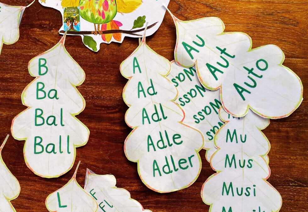 Treppenwörter auf Papier in Eichenblattform und Illustration der Eule Ada ausgelegt auf Tisch, alles aus Leselernbuch "Lesewald, Der Zauber erwacht"