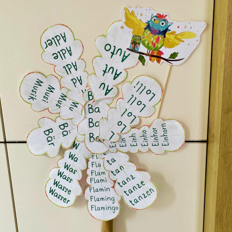 Treppenwörter auf Papier-Eichenblättern in Baumkronenform an Schrank geheftet