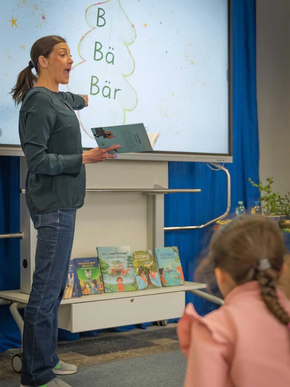Lesewald-Autorenlesung: Alexandra Wagner liest mit Kindern das Treppenwort ‚Bär‘ am Smartboard.